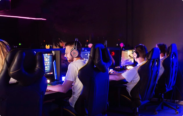 Een aantal gamers met een koptelefoon op zit achter hun gamingcomputers en neemt deel aan een online wedstrijd in een esports-club.