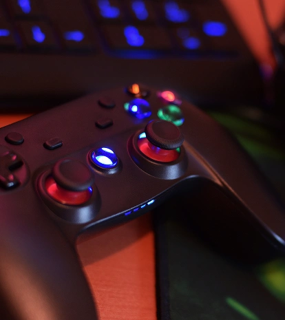 Een verlichte gamecontroller naast het toetsenbord, de muis en de gaminghoofdtelefoon op het bureau.