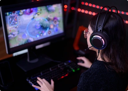 Een vrouwelijke gamer met een koptelefoon speelt op de computer een online game met RGB-verlichting.