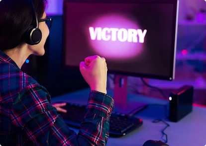 Een vrouwelijke gamer viert haar overwinning; op het scherm staat het woord ‘Victory’.